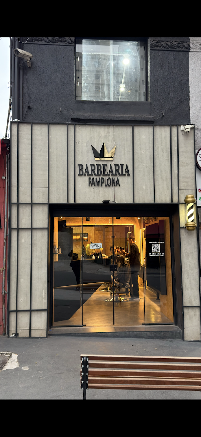 Fachada real da Barbearia Pamplona, com a coroa da marca e entrada iluminada